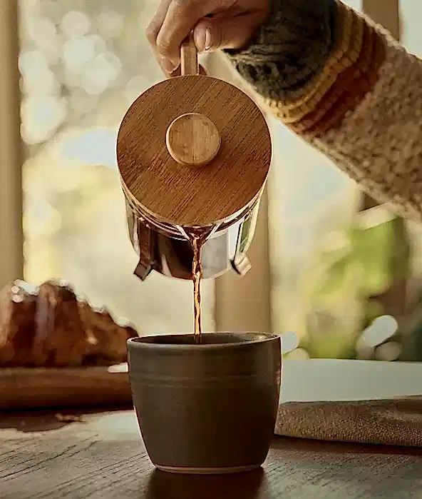 Coffee being poured into a mug from a french press